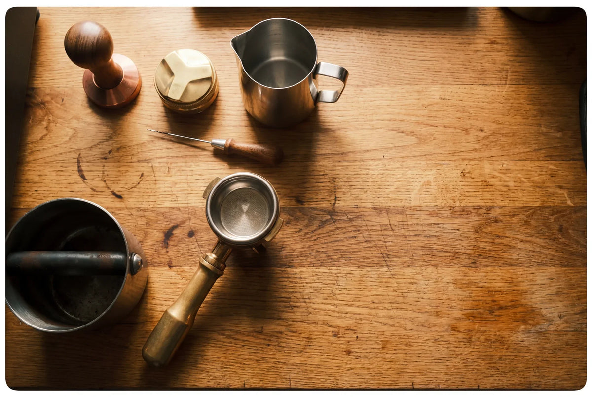 Barista tools arranged on wooden counter, tamper, pitcher and portafilter